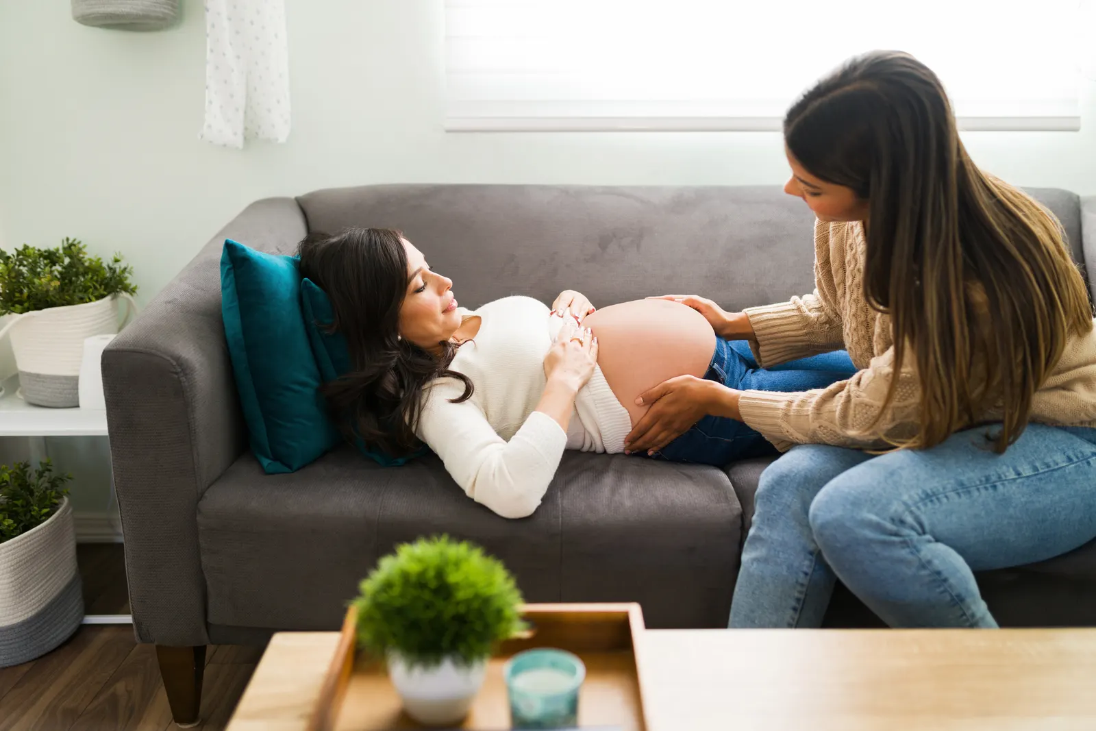 Doula accompagnant une femme enceinte allongée sur un canapé
