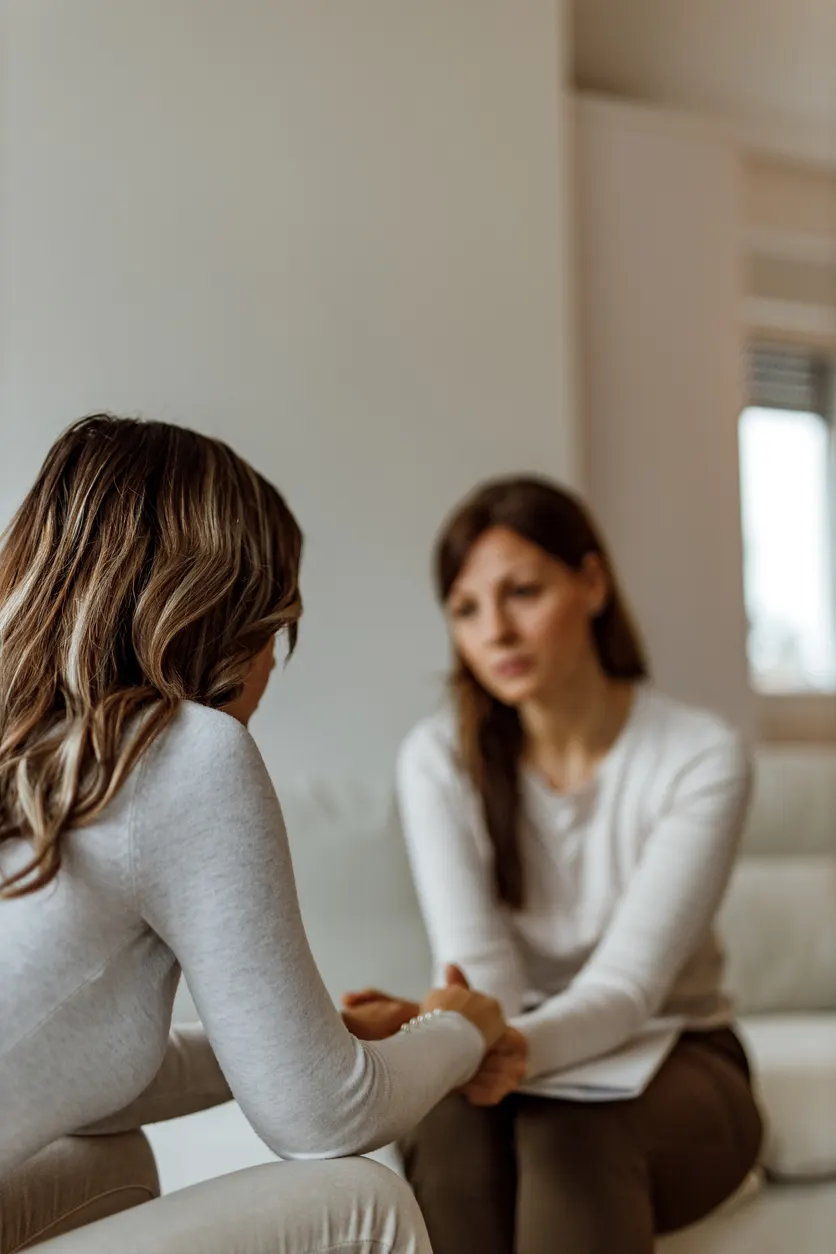 Doula tenant la main d'une femme qu'elle accompagne, assises face à face