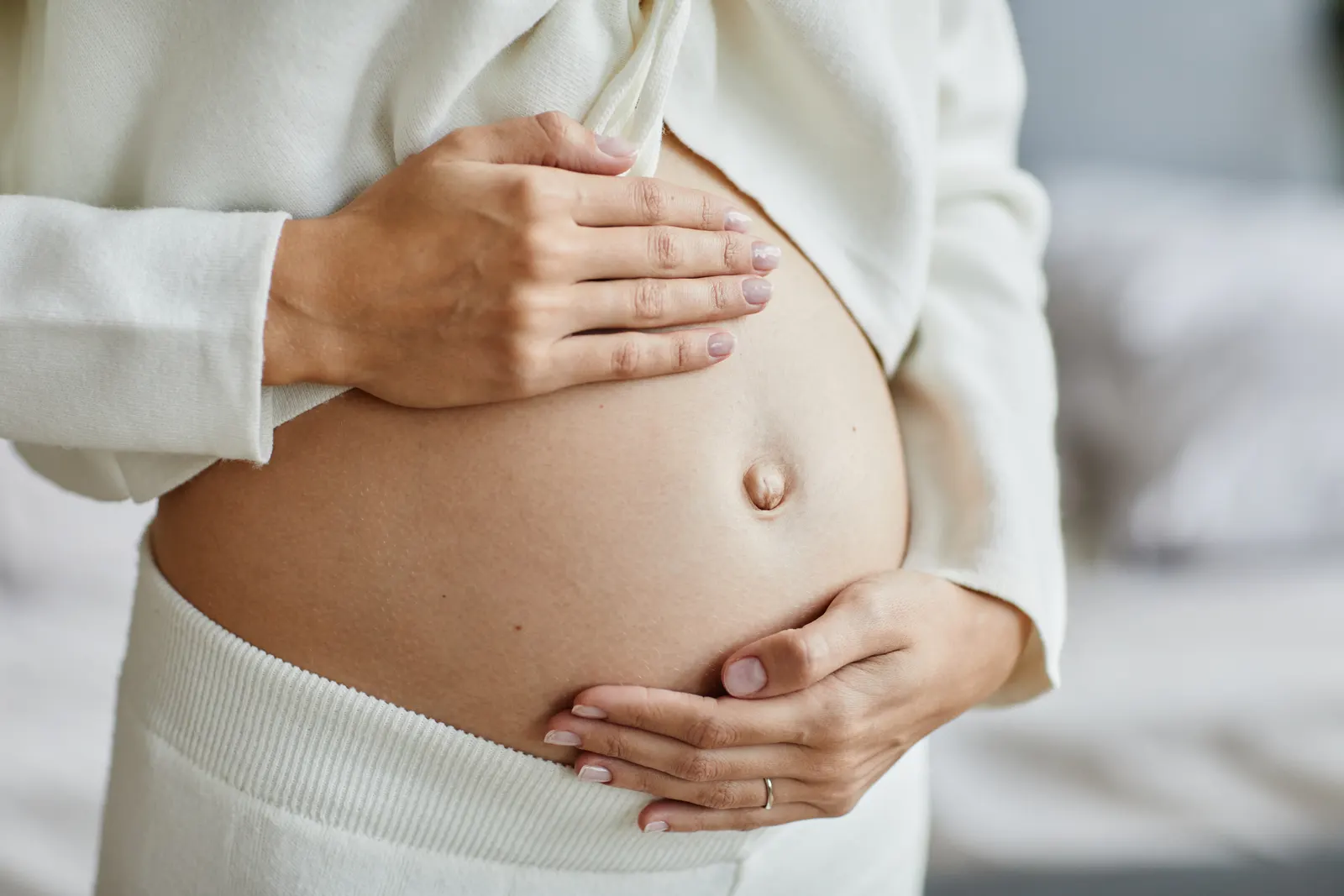 Gros plan sur des mains posées sur un ventre de femme enceinte